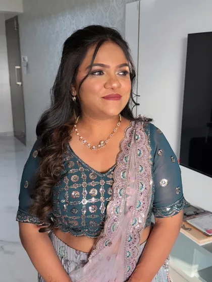 This client is ready for a reception or sangeet. Her makeup features a soft brown smokey eye and a mauve lip, complementing her teal and lavender lehenga.