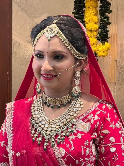 This bride chose a heavy polki choker set with green accents to go with her embroidered red bridal saree, creating a timeless and elegant look.