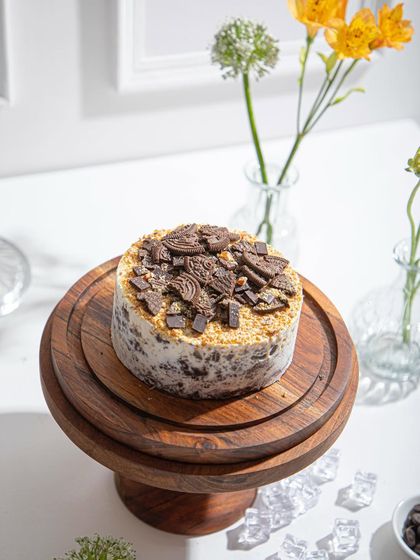 A close-up of the Cookies and Cream ice cream cake, focusing on the generous topping of crushed chocolate cookies.