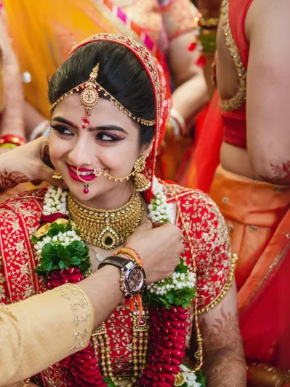 A beautiful candid moment from the wedding ceremony. The groom is adjusting the bride's varmala, and her smile shows the love and happiness of the moment.