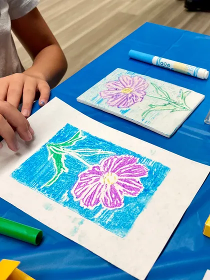 A vibrant flower print, showing the original colored foam plate and the resulting artwork. This simple printmaking technique is accessible and fun for all ages.