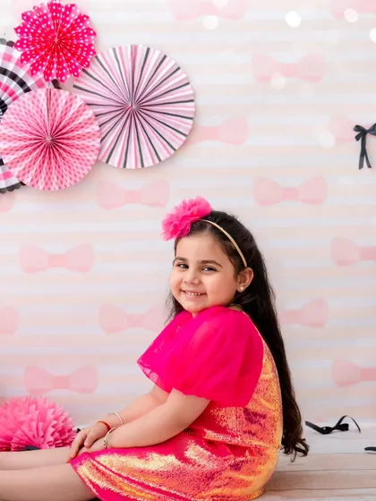 A sweet, seated portrait of a girl in a pink sequin dress, her happy smile lighting up the room.