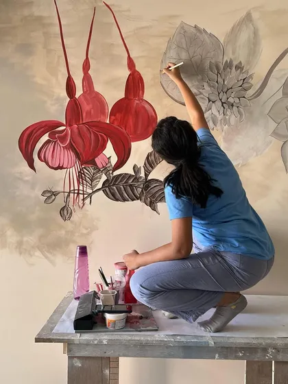 Me perched on a table to reach the top of the 'Native Grace' mural. Large-scale work often requires creative solutions and a bit of acrobatics.