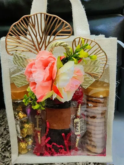 This Rakhi hamper comes in a reusable jute bag with a clear window. It contains a sipper, a jar of assorted chocolates, and a jar of cookies, along with a rakhi.