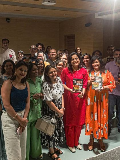 A large, smiling group of attendees and authors at a book launch event.