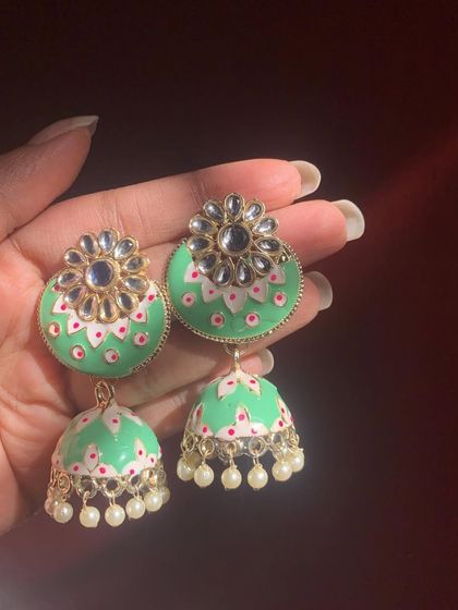 A beautiful mint green Meenakari jhumka with a Kundan stud. The delicate hand-painted details and pearl drops make this a very elegant and fresh design.