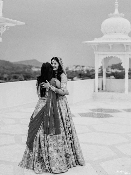A beautiful black and white shot of the bride sharing a hug with a friend or sister on a scenic terrace.