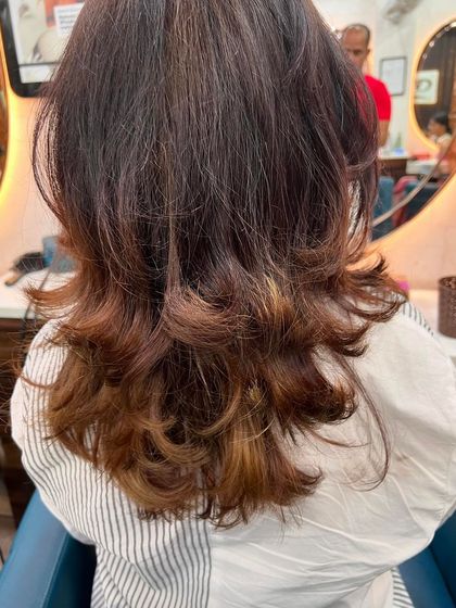 A medium-length haircut with a warm ombre effect. The color gradually transitions from a natural dark root to lighter, coppery ends.