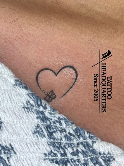 A minimalist heart outline with a tiny butterfly perched on it, a delicate and beautiful design.