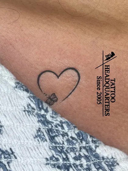 A minimalist heart outline with a tiny butterfly perched on it, a delicate and beautiful design.