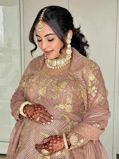 Ayushi cradling her baby bump, looking so serene and beautiful. The makeup was designed to be long-lasting and comfortable for her special day.