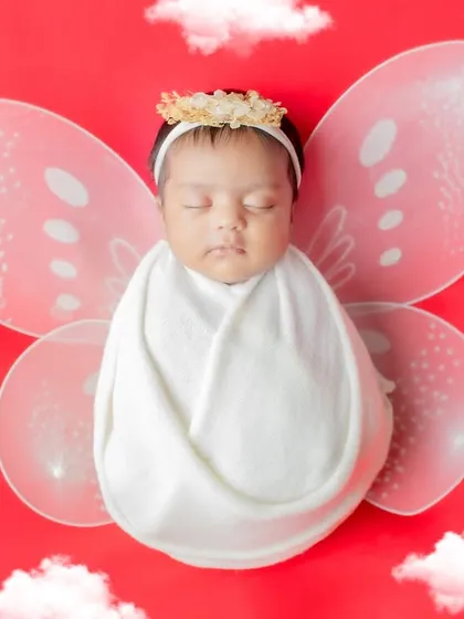 Your little butterfly, swaddled and sleeping peacefully. This whimsical setup with wings and clouds makes for a magical first portrait.