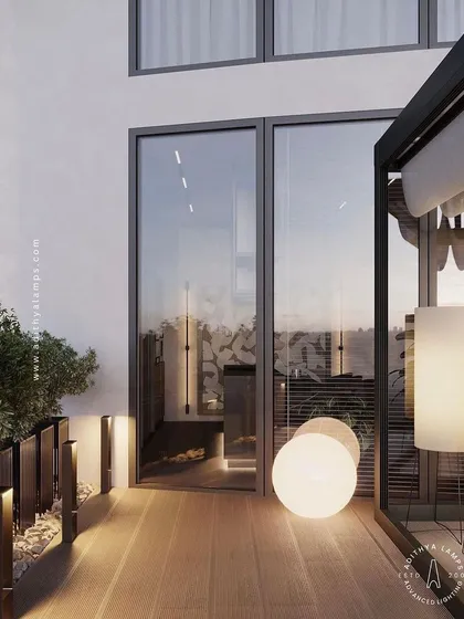 We create layered lighting schemes for outdoor spaces like this balcony. Here, a combination of glowing spherical floor lamps and low-level pathway bollards provides both ambient and functional light, turning the area into a cozy outdoor room.