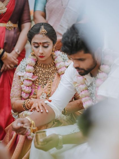 An intimate shot of a ritual being performed, the focus on the couple's hands and the sacred elements.