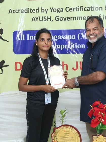 A volunteer receives a certificate of appreciation for her selfless support and hard work during our Yogasana Competition.