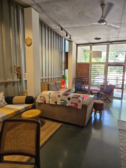 (Duplicate of 30) Another view of my living space, showing the flexible seating arrangements and the use of corrugated metal sheets on the wall, an industrial material repurposed for its textural quality.