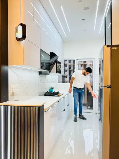 Final checks on this all-white modular kitchen at JM Florence. The design includes a built-in chimney, fluted panel details, and integrated appliances for a seamless look.