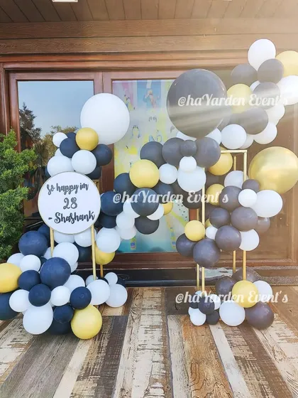 A modern and minimalist setup for a 28th birthday. The abstract balloon arrangement in black, white, and yellow creates a unique and artistic look.