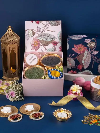 This Diwali hamper is styled against a deep blue background to make the floral packaging and golden lantern pop. The composition is designed to feel abundant and full of festive treasures.