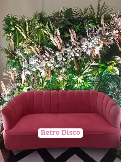 This 'Retro Disco' setup features a vibrant pink sofa against a backdrop of lush greenery, pampas grass, and disco balls. It’s a fun and trendy photo corner perfect for a Mehendi or cocktail party.