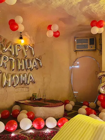 A wider view of the rustic room decoration, showing the "Happy Birthday" foil letters on the wall and balloons scattered on the floor.