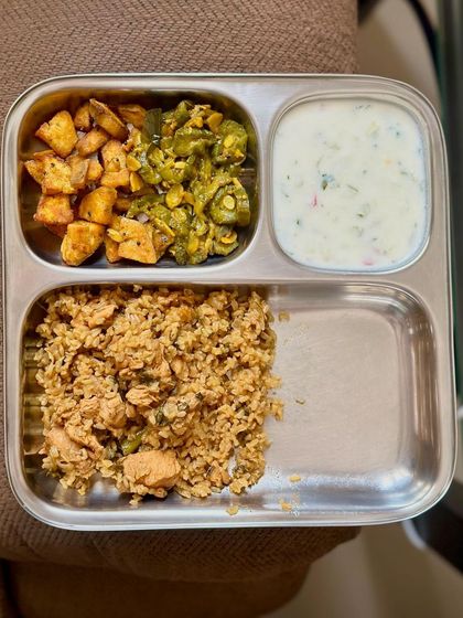 A balanced meal of chicken pulav with sautéed paneer, ivy gourd, and a side of raita.
