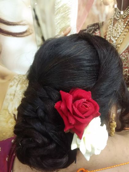 A close-up of a classic bridal bun. This twisted bun is adorned with a red and a white rose, a simple and timeless choice for a wedding ceremony.