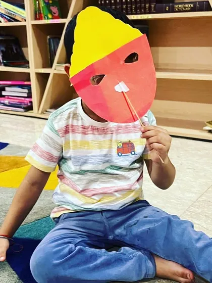 A child playfully poses with the Ravan mask he made. Our craft sessions are always filled with fun and imagination.