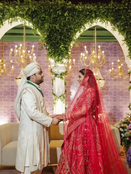 The couple, Arushi and Anirudh, share a moment during their Greek themed wedding ceremony. The backdrop features classic arches draped in greenery, creating a timeless and romantic setting for their vows.