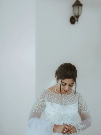 A quiet, contemplative portrait of the bride in her beautiful gown against a simple white wall.