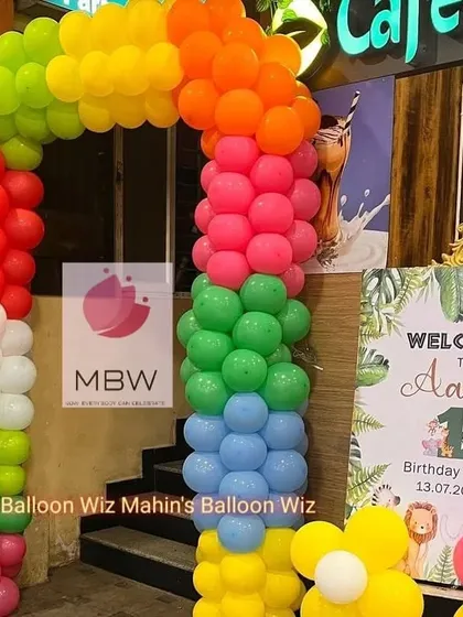 A vibrant rainbow balloon arch at the entrance of a cafe, setting a cheerful and festive tone for the birthday celebration inside.