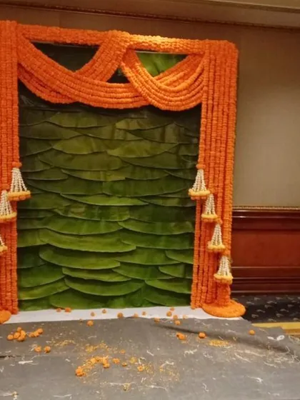 A classic combination for any puja or festival, this backdrop features vibrant marigold garlands framing a wall of fresh banana leaves.