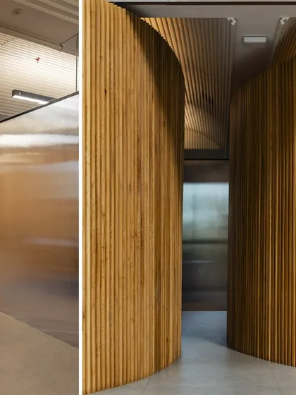The updated design for the UTI HQ includes these large, pivoting wooden doors, which add a sense of grandeur and material warmth to the corporate space.