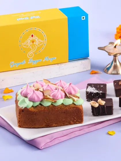 A festive gift box for Ganpati featuring a rose pista teacake and assorted chocolate treats.