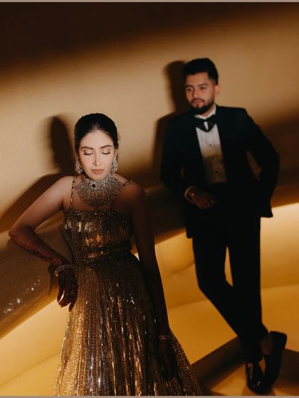 A stylish, editorial-style portrait of Shrey and Ragini at their engagement. The use of architectural lines and warm lighting creates a modern, sophisticated, and cinematic feel.