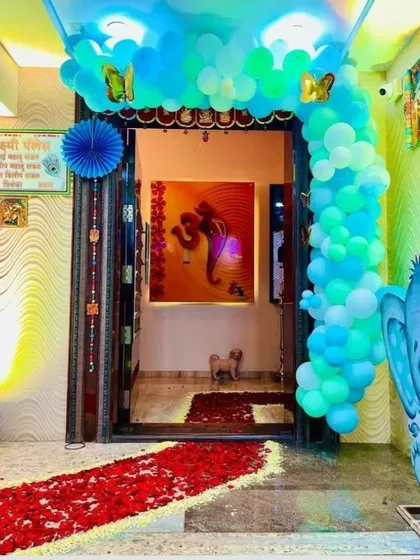 A beautiful home entrance decorated to welcome a new baby. A blue and green balloon arch and a path of rose petals create a warm and festive greeting.