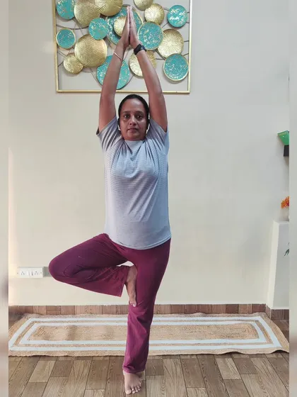 A student holds Vrikshasana (Tree Pose). This classic balancing pose improves focus, strengthens the legs and ankles, and helps to create a sense of grounding and stability.