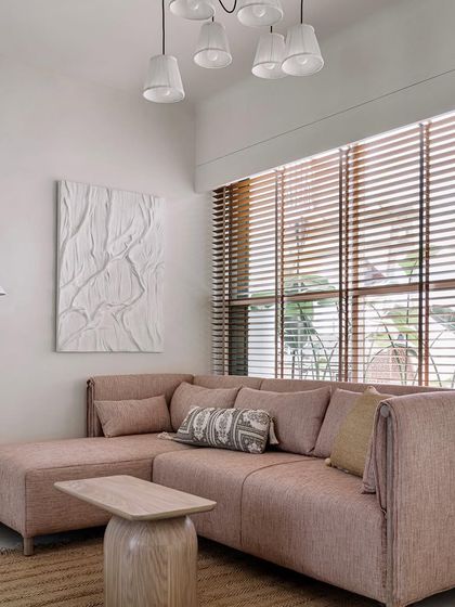 The guest bedroom is a calming space with a dusty pink sofa, natural fiber rug, and large windows that let in plenty of light.