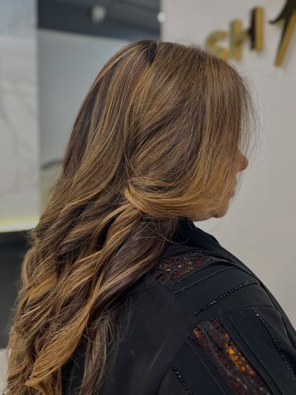 A stunning blend of light brown and blonde, styled with soft curls to show off the dimension of the highlights.