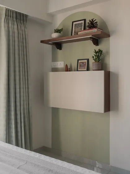 A space-saving floating cabinet is set within a sage-green arched niche, creating a beautiful and functional corner in this bedroom.