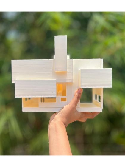 A hand holds a 3D-printed model of an industrial building against a natural backdrop. This juxtaposition of the "thinking hand" and the environment reflects our core design philosophy.