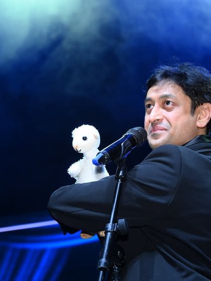 A candid shot of me performing with a small finger puppet at the European Marathi Sammelan, a show where my whole family participated.