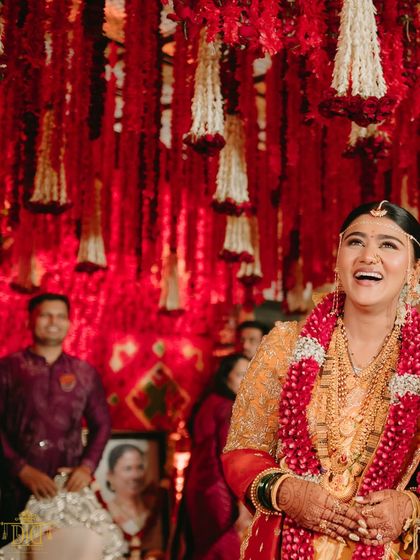 The pure joy on the bride's face during her Marathi wedding ceremony. The backdrop of hanging red and white floral strings was designed to create a vibrant and celebratory atmosphere, perfectly complementing the emotional moments of the day.