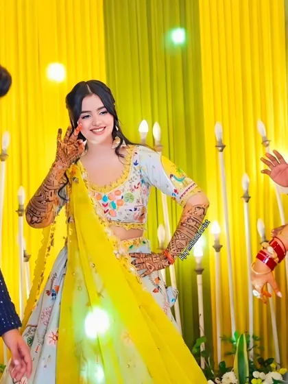A fun, candid moment from a wedding celebration, with the bride's beautiful mehndi on full display as she dances.