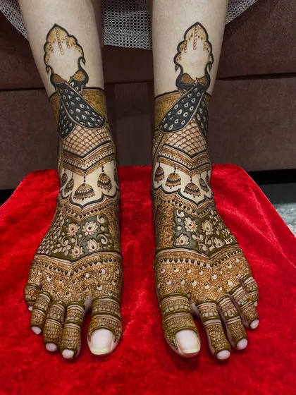 The same peacock feet design, shown against a vibrant red background. The contrast makes the intricate details of the henna pop.