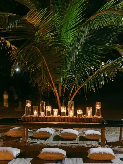 A welcome dinner experience on the sand. We used barefoot seating with plush cushions, dozens of candles in glass votives, and the natural backdrop of tropical palms to create a moment rooted in culture and warmed with emotion.