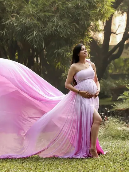 The magnificent train of the pink gown flowing in the breeze creates a sense of movement and magic in this beautiful outdoor maternity portrait.
