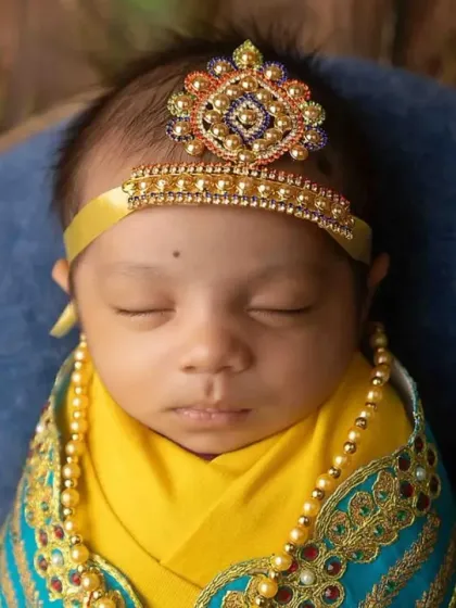 A detailed close-up of the baby's face and the beautiful, handcrafted crown for the Little Krishna theme.