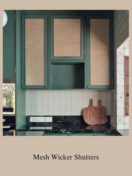 A detail shot of the green cabinets with wicker inserts and the dark marble countertop. The contrast between the natural wicker and the polished stone is both striking and harmonious.