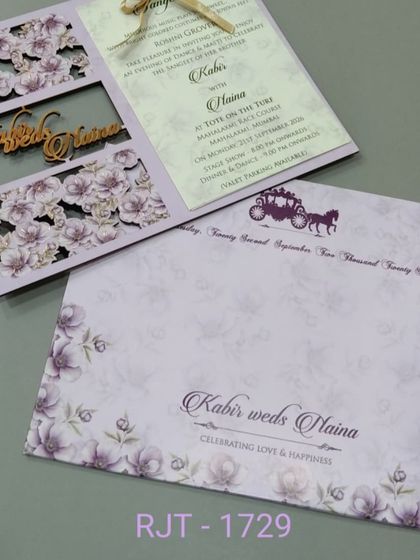 This lavender invitation has a laser-cut floral window design with the couple's names in a gold cutout. The design is delicate and modern, perfect for a stylish wedding.